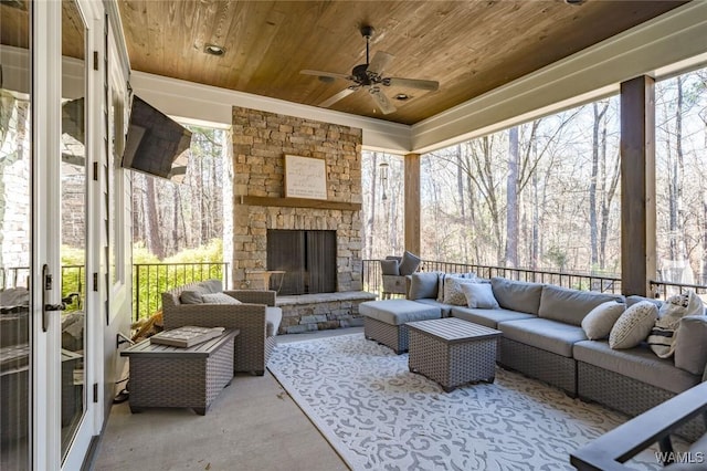 sunroom / solarium featuring an outdoor stone fireplace, a wealth of natural light, wooden ceiling, and ceiling fan