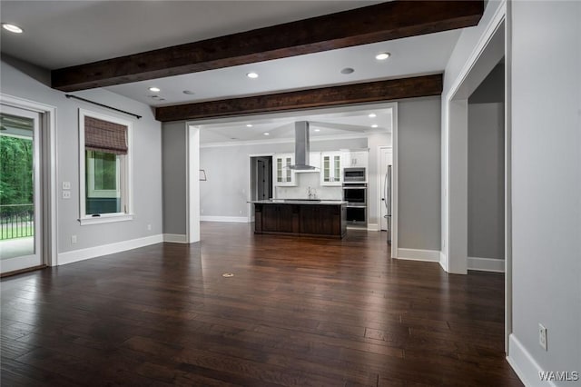 unfurnished living room with dark wood-type flooring, recessed lighting, baseboards, and beam ceiling