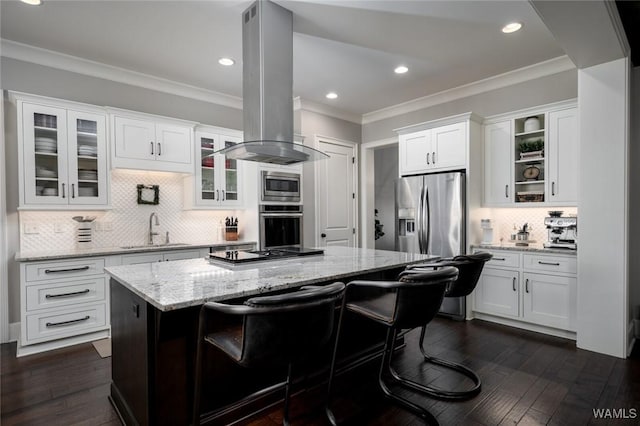 kitchen with white cabinets, sink, appliances with stainless steel finishes, island range hood, and a kitchen bar