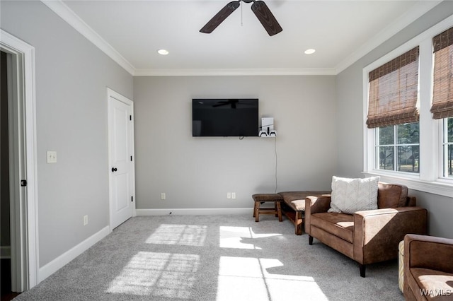 living area with ceiling fan, crown molding, and light carpet