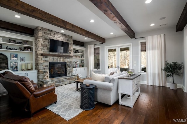 living room featuring beamed ceiling, built in shelves, dark hardwood / wood-style flooring, and a fireplace