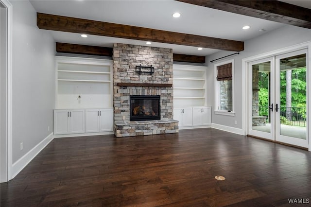 unfurnished living room with beam ceiling, a stone fireplace, french doors, baseboards, and dark wood-style floors