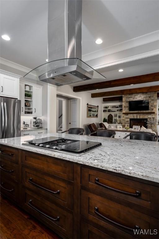 kitchen with island exhaust hood, appliances with stainless steel finishes, light stone counters, and a fireplace