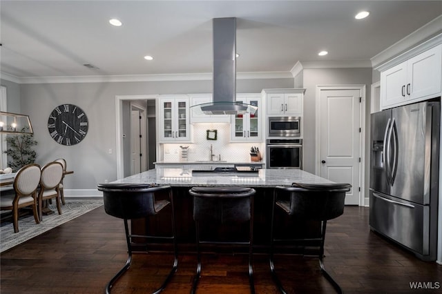 kitchen featuring light stone counters, white cabinetry, island exhaust hood, and appliances with stainless steel finishes