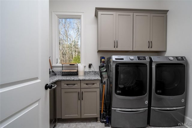 clothes washing area featuring separate washer and dryer and cabinets