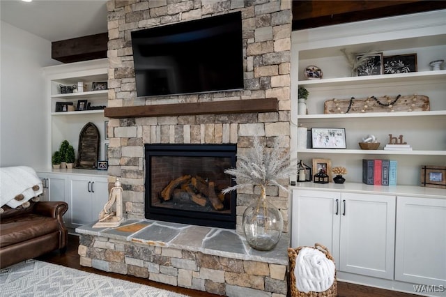 living room featuring dark hardwood / wood-style flooring, a stone fireplace, and built in features