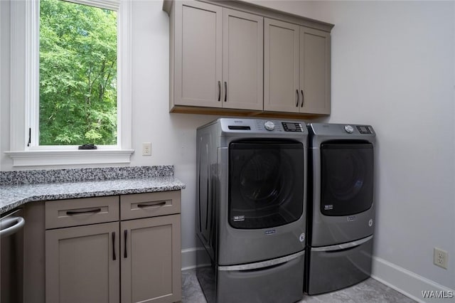 laundry area with cabinet space, baseboards, a wealth of natural light, and washing machine and clothes dryer