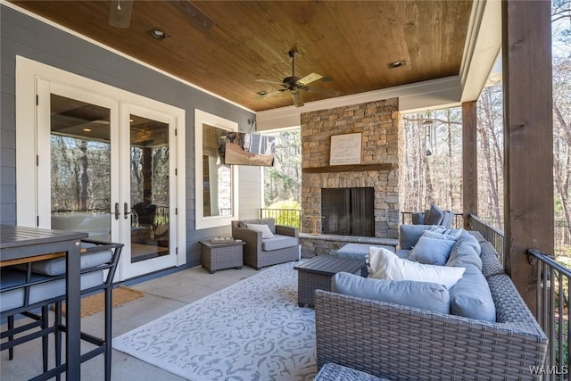 view of patio / terrace with an outdoor living space with a fireplace, french doors, and ceiling fan