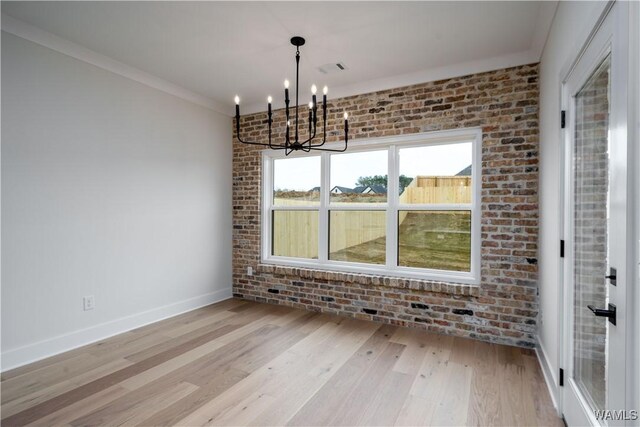 13947 Glenview Dr, Northport, AL 35475 - unfurnished dining area with an inviting chandelier, ornamental molding, baseboards, brick wall, and light wood finished floors