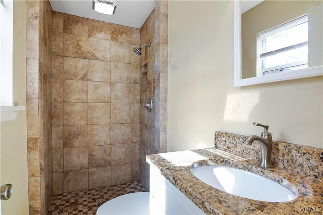 bathroom with vanity, toilet, and tiled shower