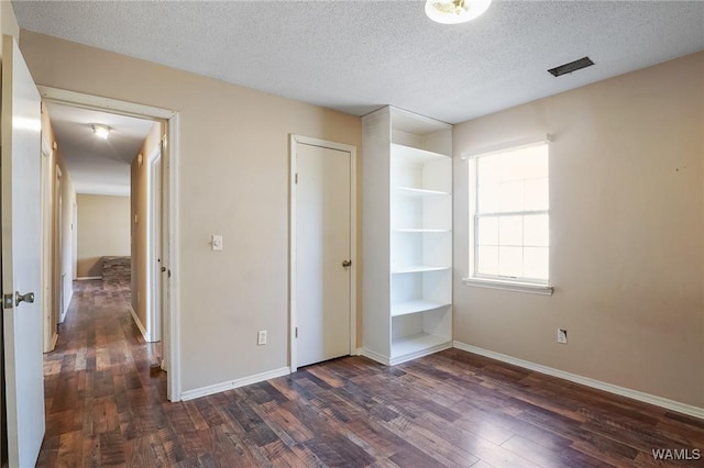 unfurnished bedroom featuring dark wood-type flooring, a closet, and a textured ceiling