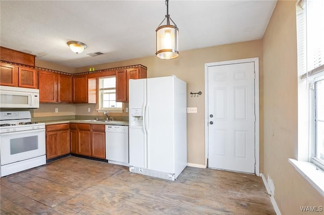 kitchen featuring light wood-type flooring, sink, white appliances, and decorative light fixtures