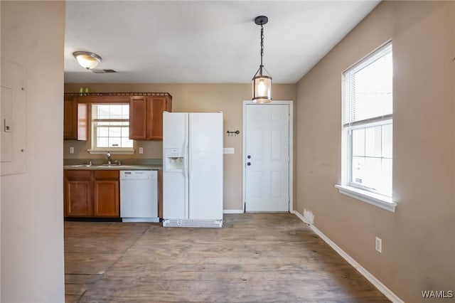 kitchen with pendant lighting, white appliances, sink, and light wood-type flooring