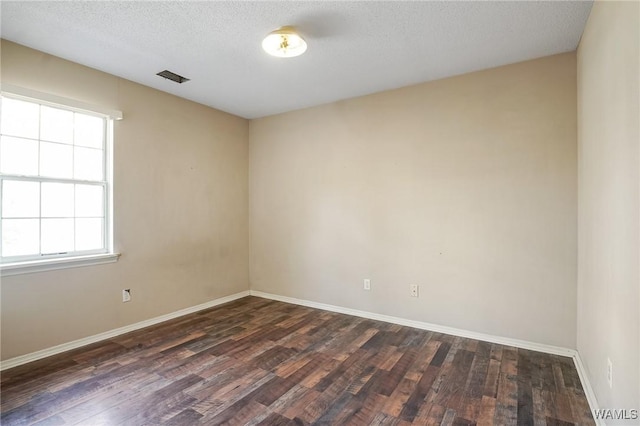 spare room featuring dark hardwood / wood-style floors and a textured ceiling