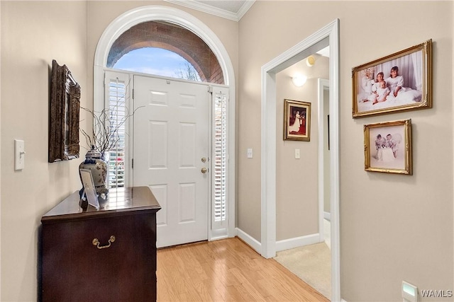 foyer entrance with crown molding and light hardwood / wood-style flooring