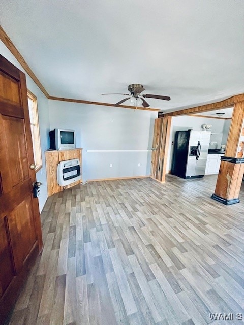 unfurnished living room featuring heating unit, ceiling fan, ornamental molding, and light hardwood / wood-style flooring