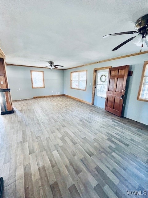 unfurnished living room with wood-type flooring, plenty of natural light, and ornamental molding