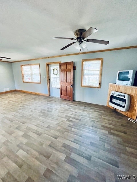 unfurnished living room featuring ornamental molding, heating unit, plenty of natural light, and light hardwood / wood-style floors