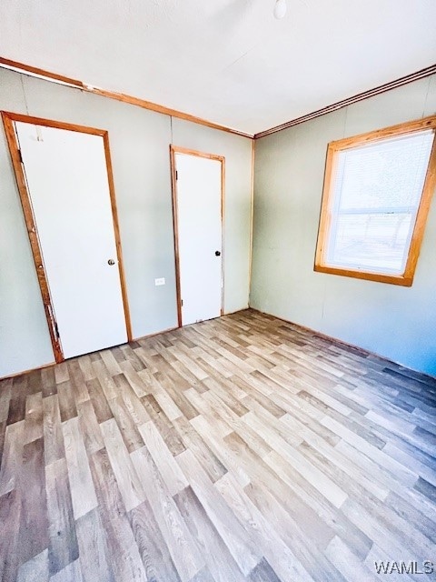 unfurnished bedroom featuring light hardwood / wood-style flooring, a closet, and crown molding