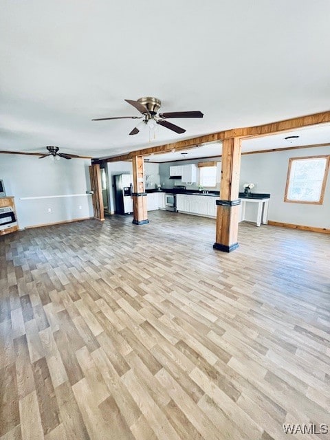 basement featuring ceiling fan, light hardwood / wood-style floors, and white refrigerator with ice dispenser