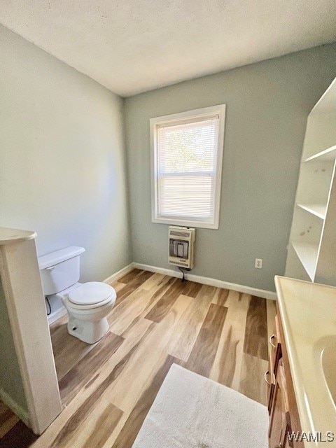 bathroom featuring vanity, toilet, wood-type flooring, and heating unit