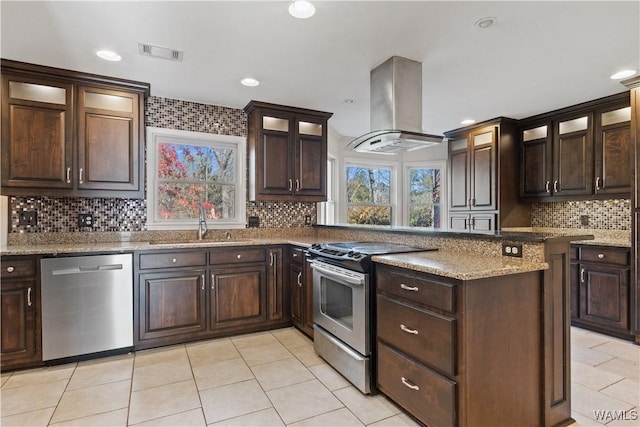 kitchen featuring sink, dark brown cabinets, stainless steel appliances, island exhaust hood, and decorative backsplash