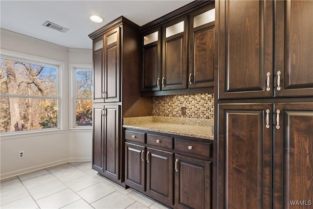 kitchen with dark brown cabinetry, light tile patterned floors, decorative backsplash, and light stone countertops