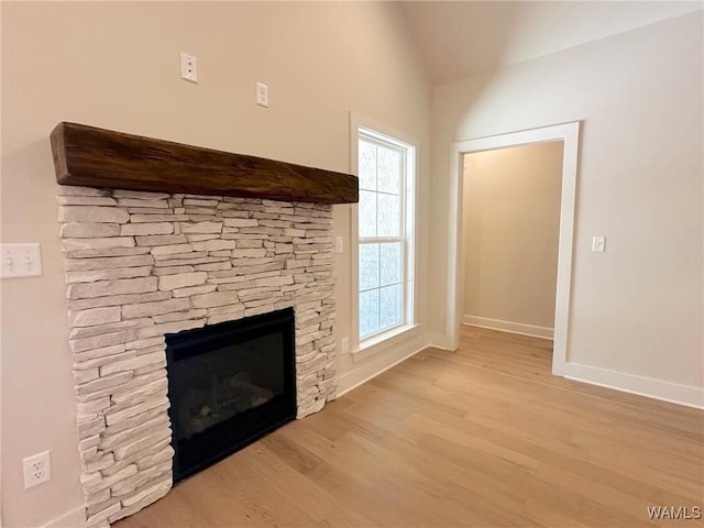 unfurnished living room featuring light wood-type flooring, a fireplace, and vaulted ceiling