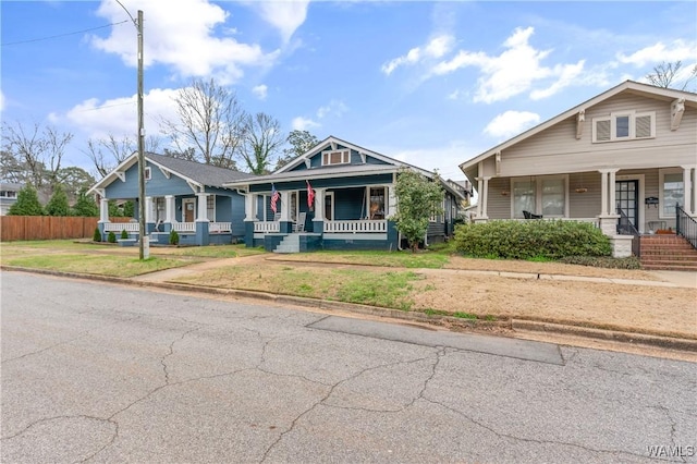 bungalow-style house featuring covered porch, a front lawn, and fence