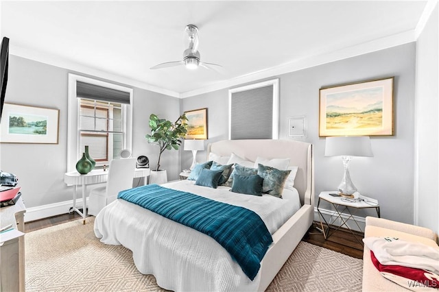 bedroom featuring a ceiling fan, baseboards, wood finished floors, and ornamental molding