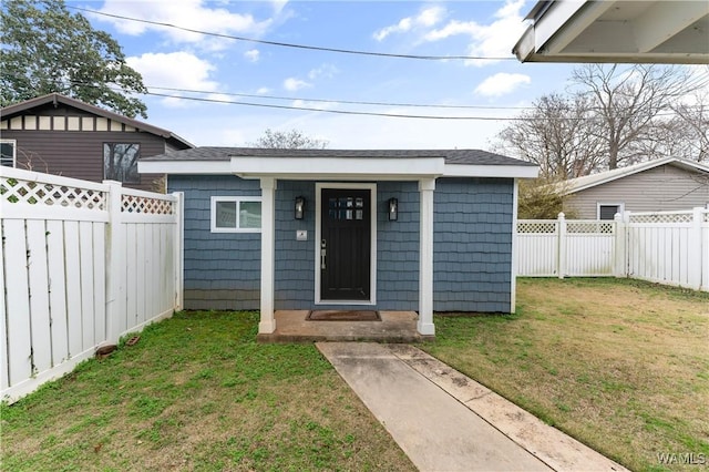 entrance to property featuring a lawn and fence