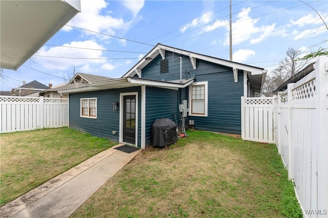 rear view of property featuring a yard and a fenced backyard