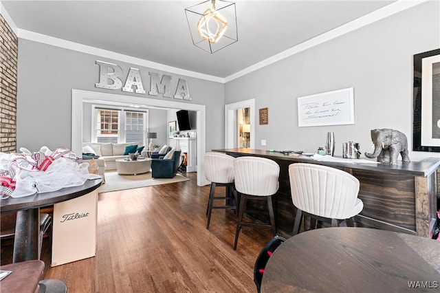 dining room with crown molding, an inviting chandelier, and wood finished floors