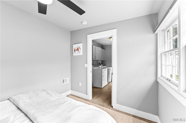 bedroom featuring wood finished floors, a ceiling fan, visible vents, baseboards, and washer and clothes dryer