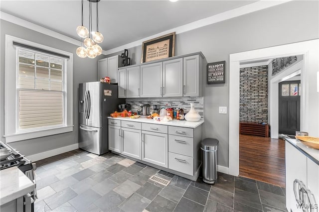 kitchen featuring black range with gas cooktop, stone finish floor, gray cabinets, and stainless steel fridge with ice dispenser