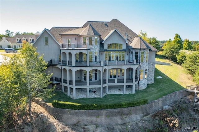 back of property featuring a balcony and a lawn