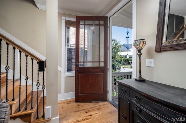 entryway with light wood-type flooring and ornamental molding