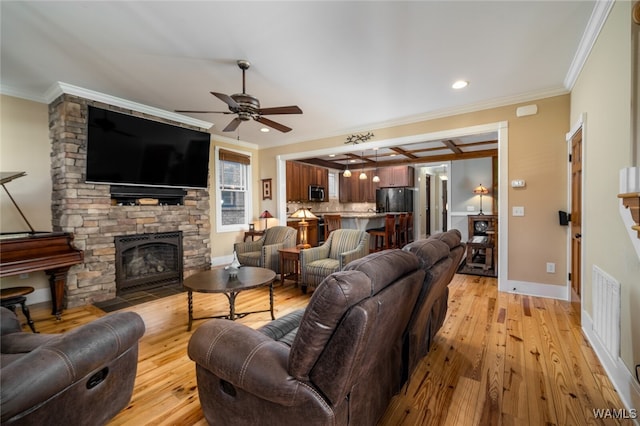 living room featuring ceiling fan, a fireplace, light wood-type flooring, and crown molding