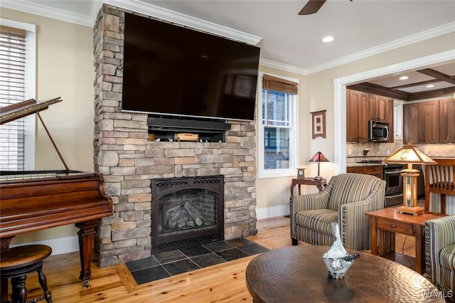 living room featuring a fireplace, crown molding, hardwood / wood-style floors, and ceiling fan