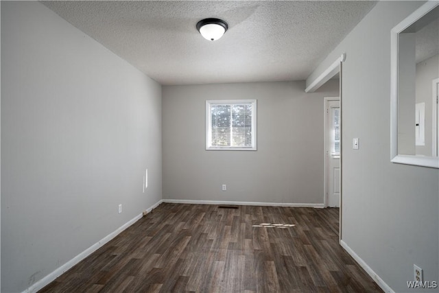 empty room featuring a textured ceiling, baseboards, and wood finished floors