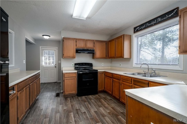 kitchen with light countertops, dark wood-type flooring, a sink, black range with electric cooktop, and under cabinet range hood