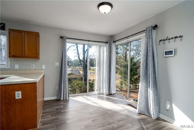 doorway with a textured ceiling, baseboards, and wood finished floors