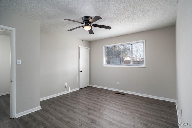 spare room with visible vents, ceiling fan, a textured ceiling, wood finished floors, and baseboards