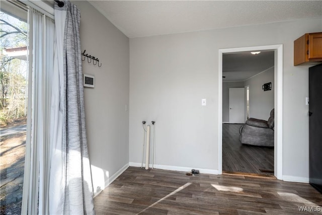 unfurnished room featuring a textured ceiling, baseboards, and dark wood-style flooring