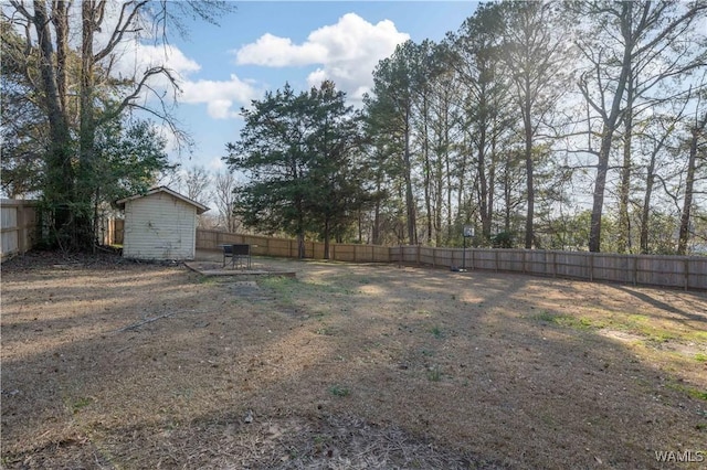 view of yard with a fenced backyard, a storage unit, and an outdoor structure