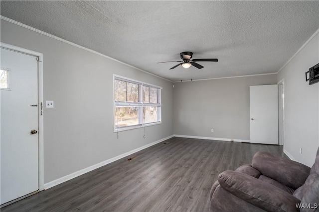 unfurnished living room featuring crown molding, dark wood finished floors, ceiling fan, a textured ceiling, and baseboards