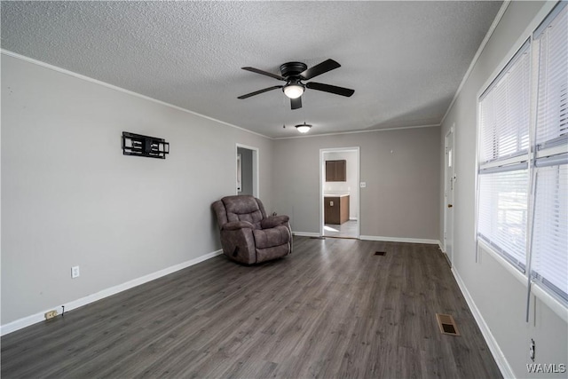 unfurnished room featuring a textured ceiling, ornamental molding, wood finished floors, and visible vents