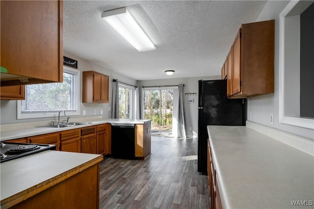 kitchen featuring a peninsula, a sink, light countertops, black appliances, and dark wood finished floors