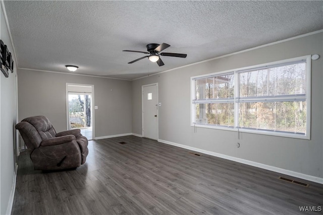 living area featuring dark wood-style flooring, a ceiling fan, baseboards, visible vents, and crown molding