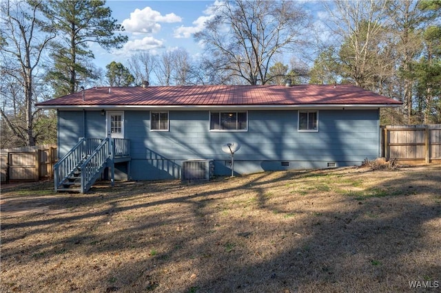 back of property with metal roof, a yard, crawl space, and fence